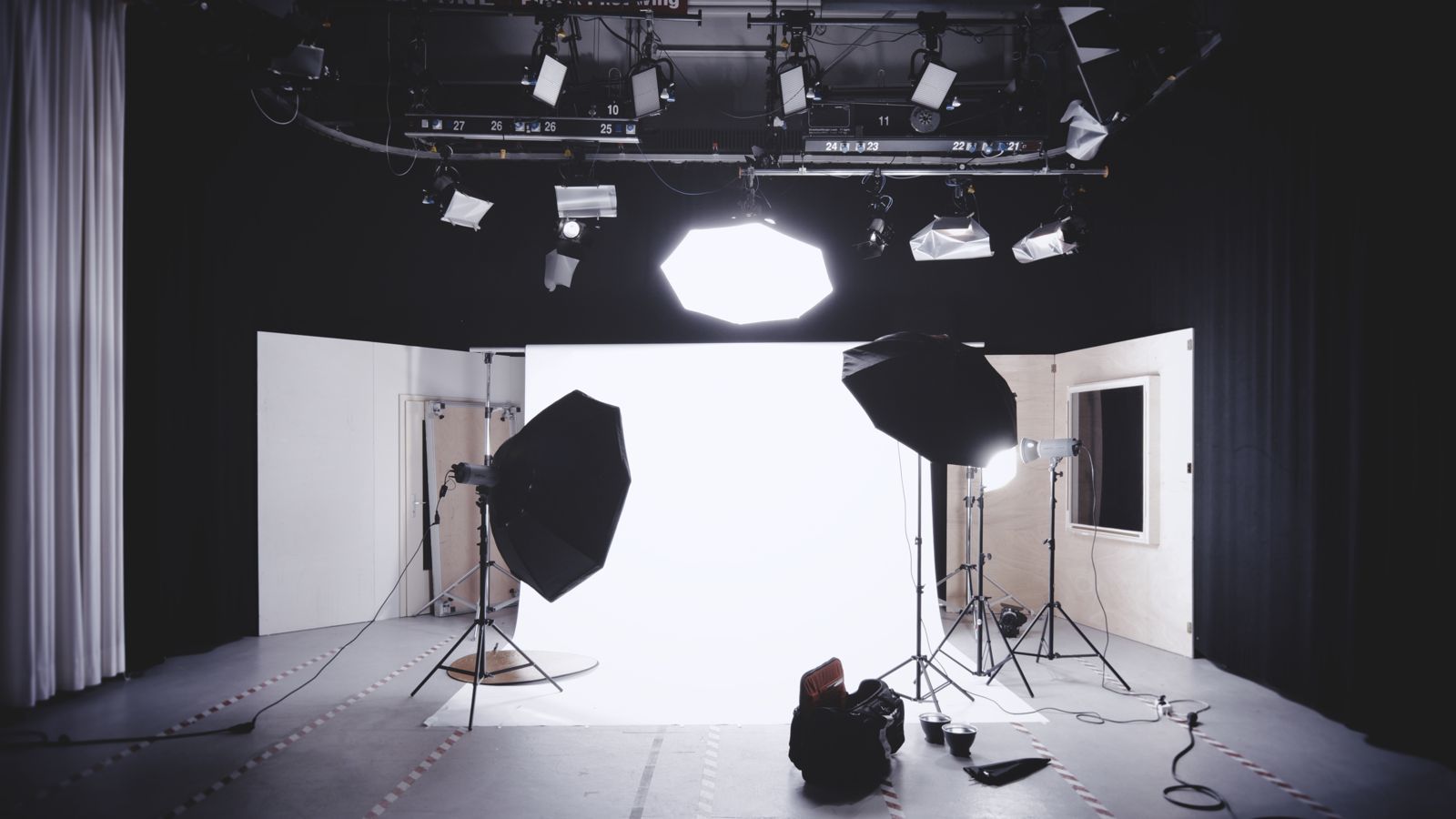 A photo studio with a white backdrop, softboxes and lights